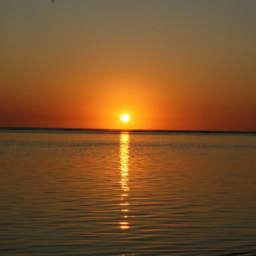 a large body of water with a sunset in the background